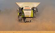 Claas Lexion combine disappearing into the dust leaving a trimmed stubble carpet in its wake.