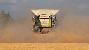 Claas Lexion combine disappearing into the dust leaving a trimmed stubble carpet in its wake.